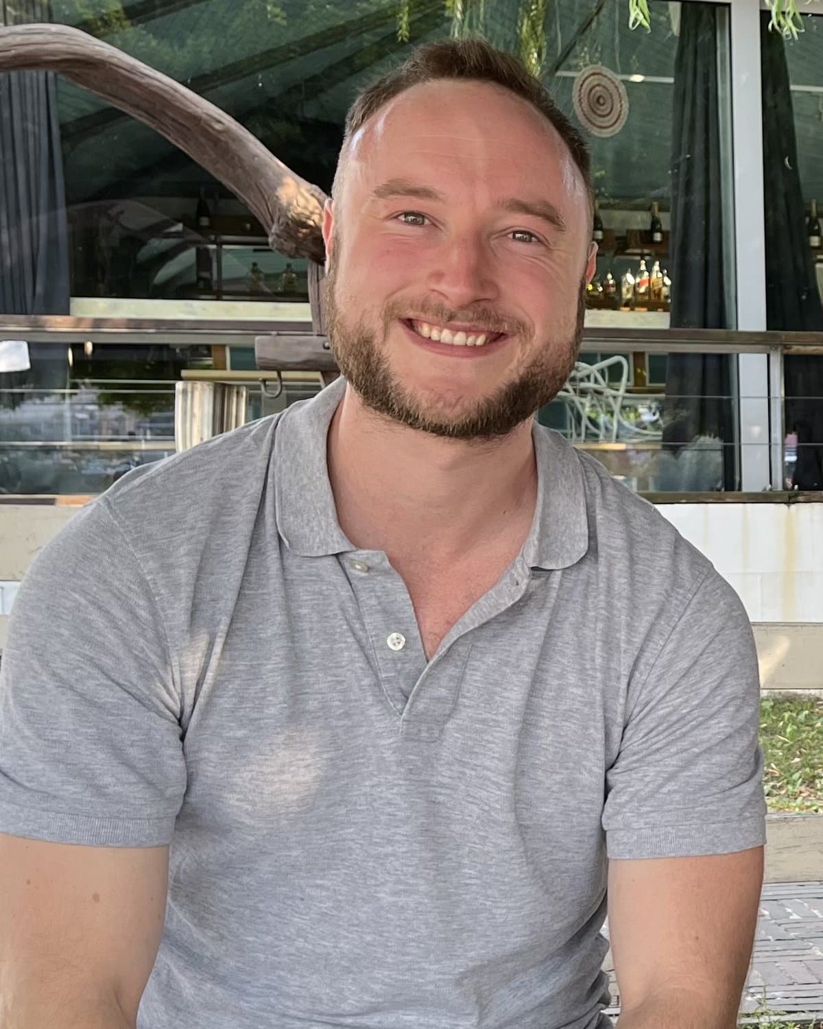 Jacob smiling, sitting outside a cafe